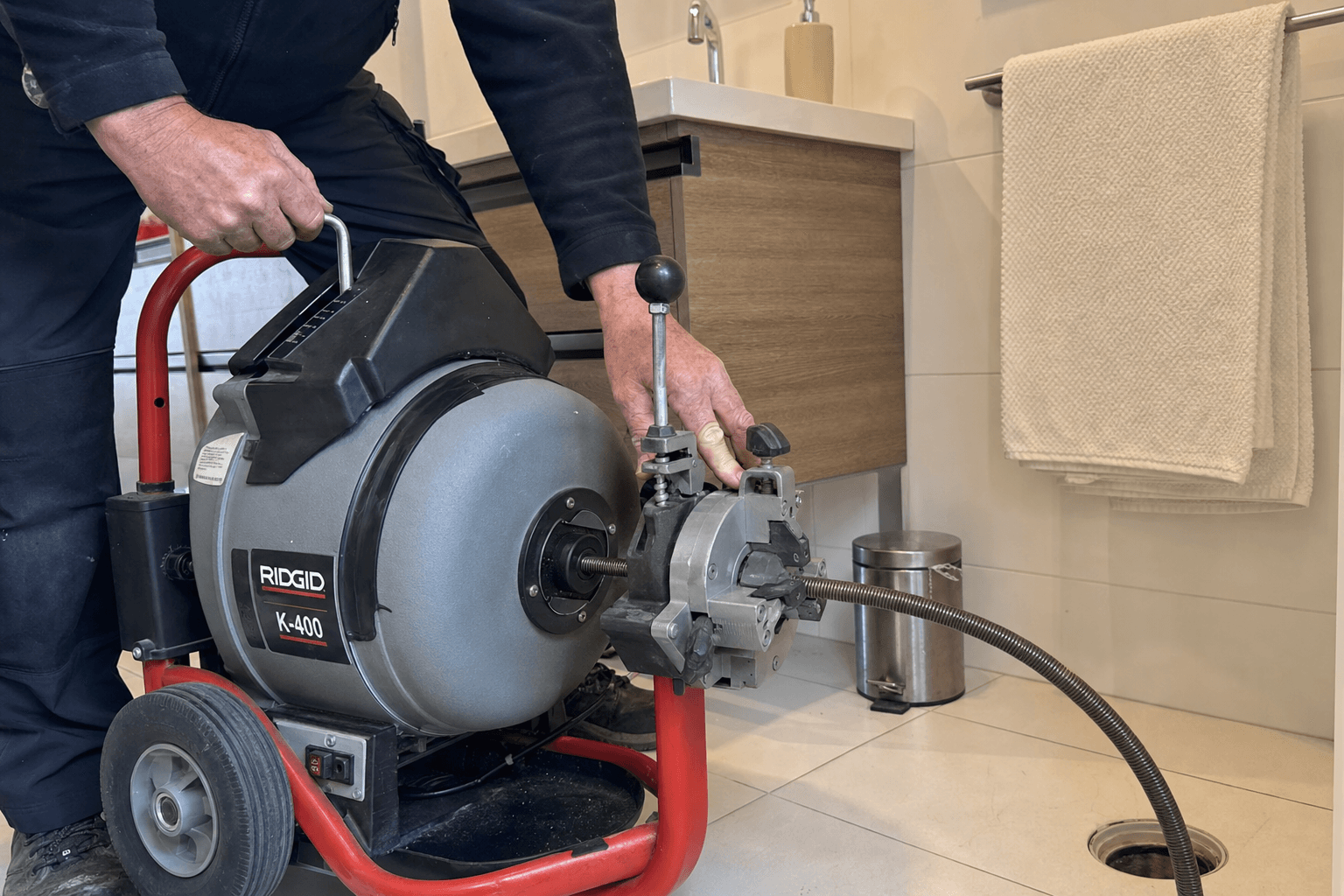 Verstopte afvoer wordt ontstopt met professionele apparatuur in een Amsterdamse badkamer